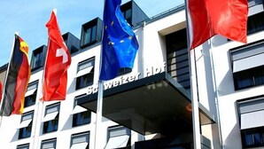 Un bâtiment d’hôtel arborant plusieurs drapeaux, dont le drapeau suisse, et sur lequel on peut lire l’inscription « Weiz Hotel » sur la façade.