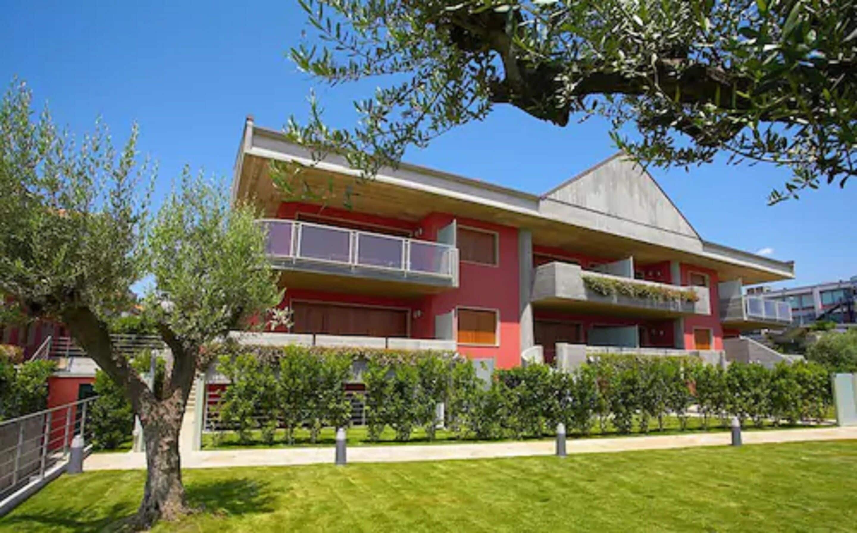 A modern building with a flat roof, large windows, and a red facade.