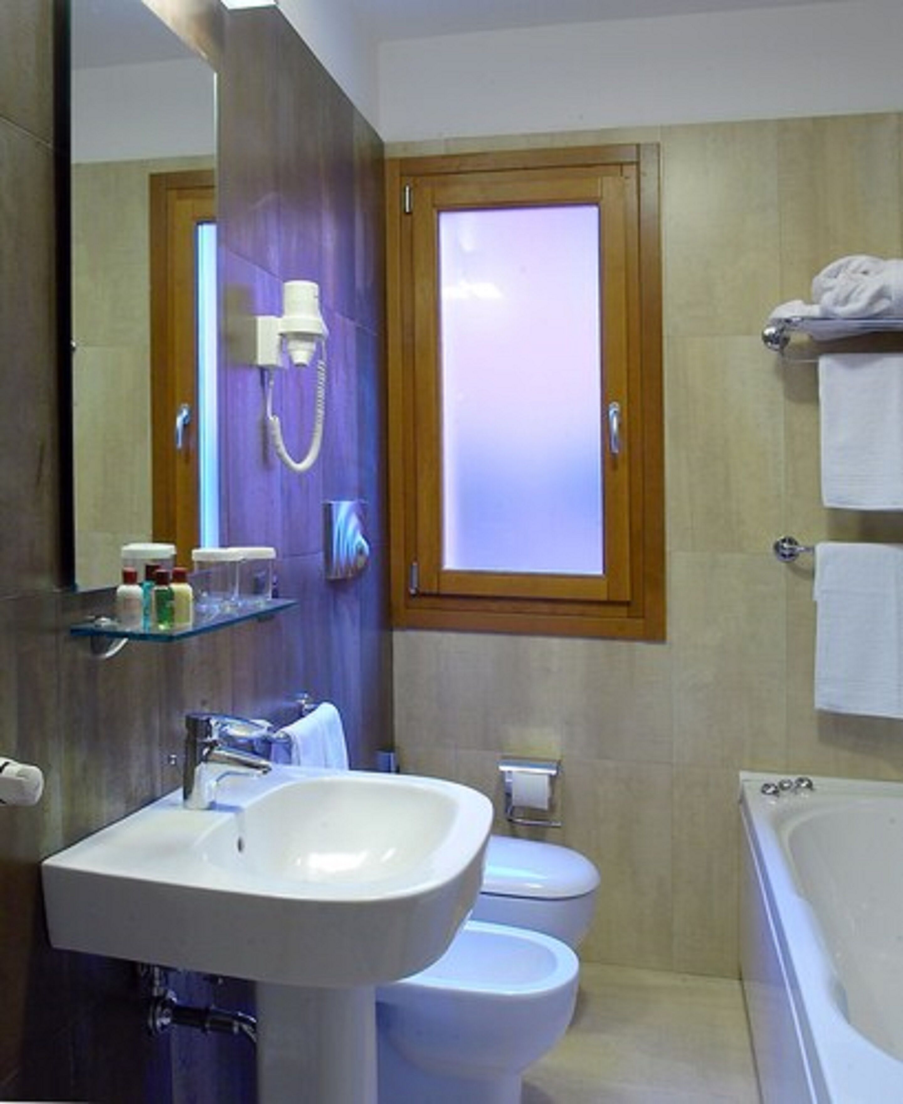 Un baño con un espejo grande, un lavamanos, un inodoro y una bañera.