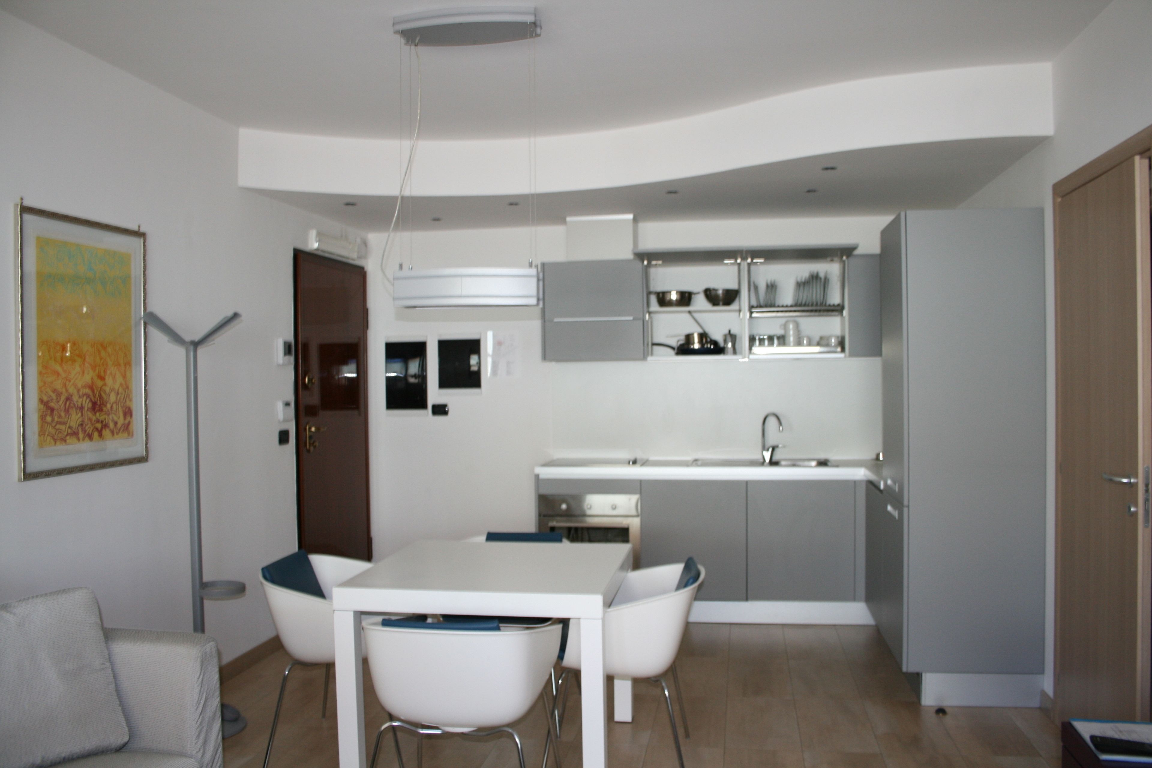 Een kleine keuken met een eethoek, inclusief een tafel, stoelen, een koelkast en kastjes.