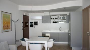 Cocina compacta con zona de comedor, que incluye una mesa, sillas, un refrigerador y armarios.