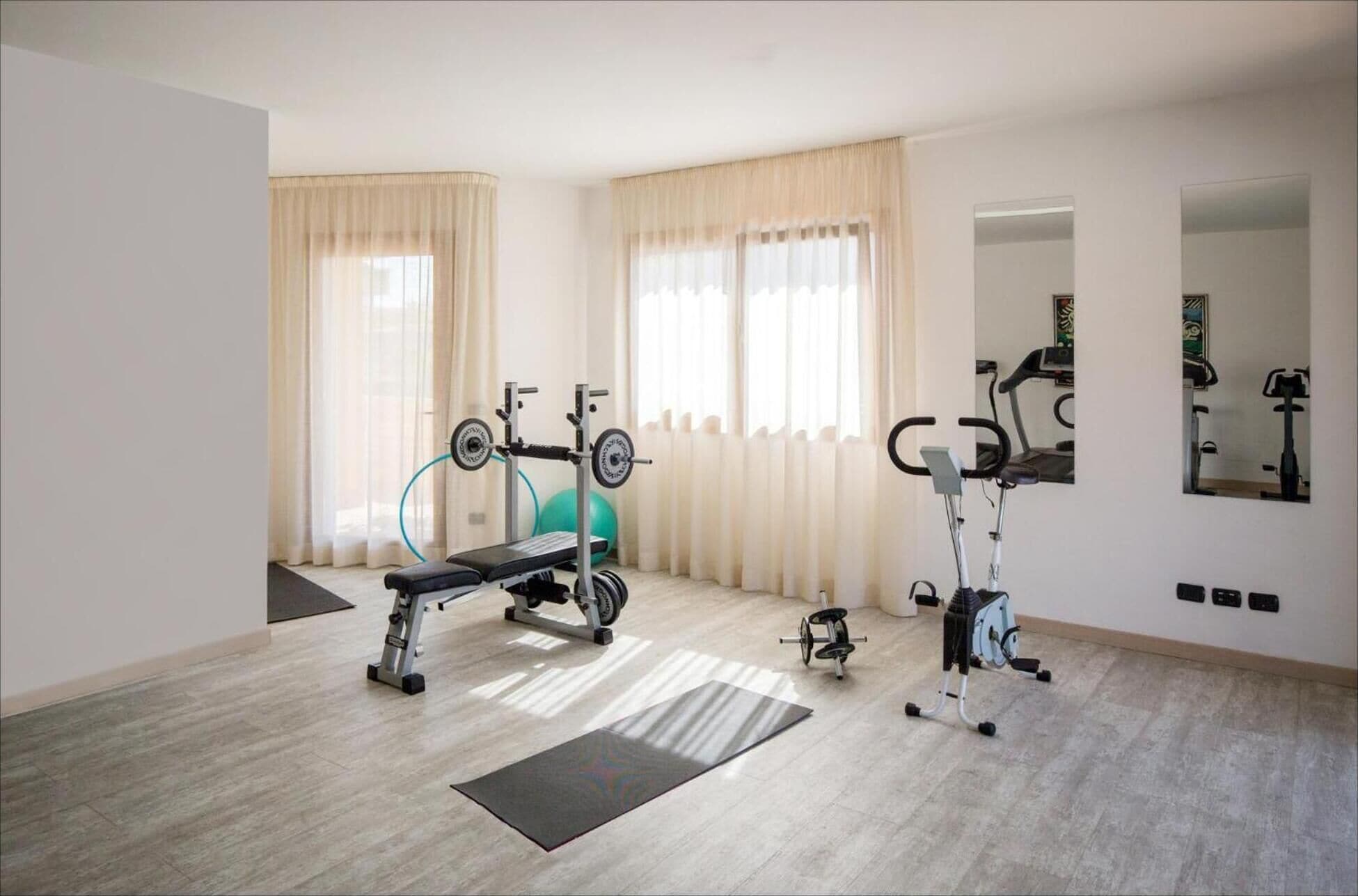 A spacious room with a weight bench, a rowing machine, and a stationary bike.
