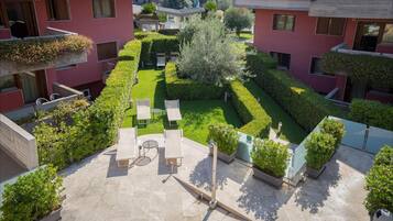 Un patio con césped, zona de estar y plantas en macetas.