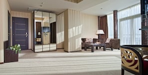 A hotel room with a large mirror, a sofa, a coffee table, and a chair.