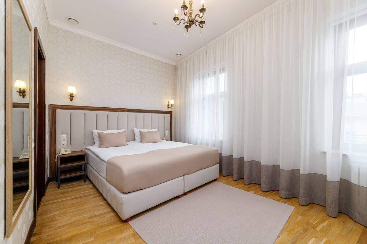 Un dormitorio con una cama grande, una mesita de noche, un espejo y una araña.