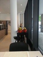 Um interior moderno com área de jantar, apresentando uma mesa com plantas em vasos, uma cadeira preta e vista por uma grande janela.