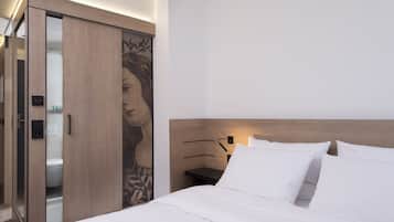 Una habitación de hotel moderna con cabecera de madera, un espejo grande y un armario con diseño floral.
