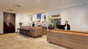 Un área de recepción moderna con un mostrador de madera, taburetes de bar y un retrato grande en la pared.