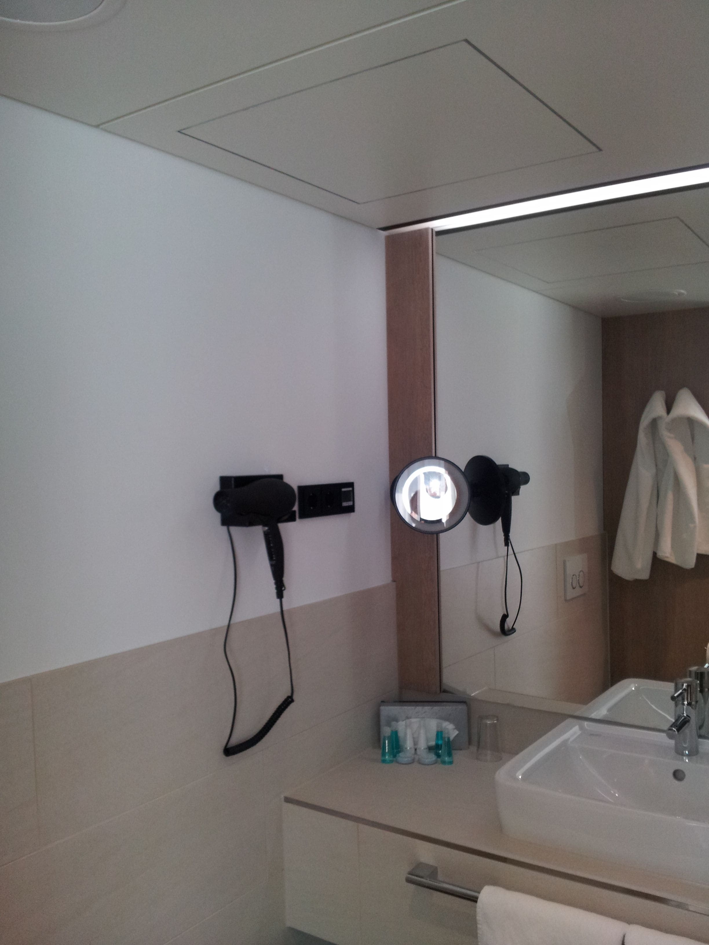A bathroom with a sink, mirror, hairdryer, and towel rack.