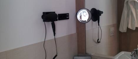 Un baño con lavamanos, espejo, secador de pelo y barra para toallas.