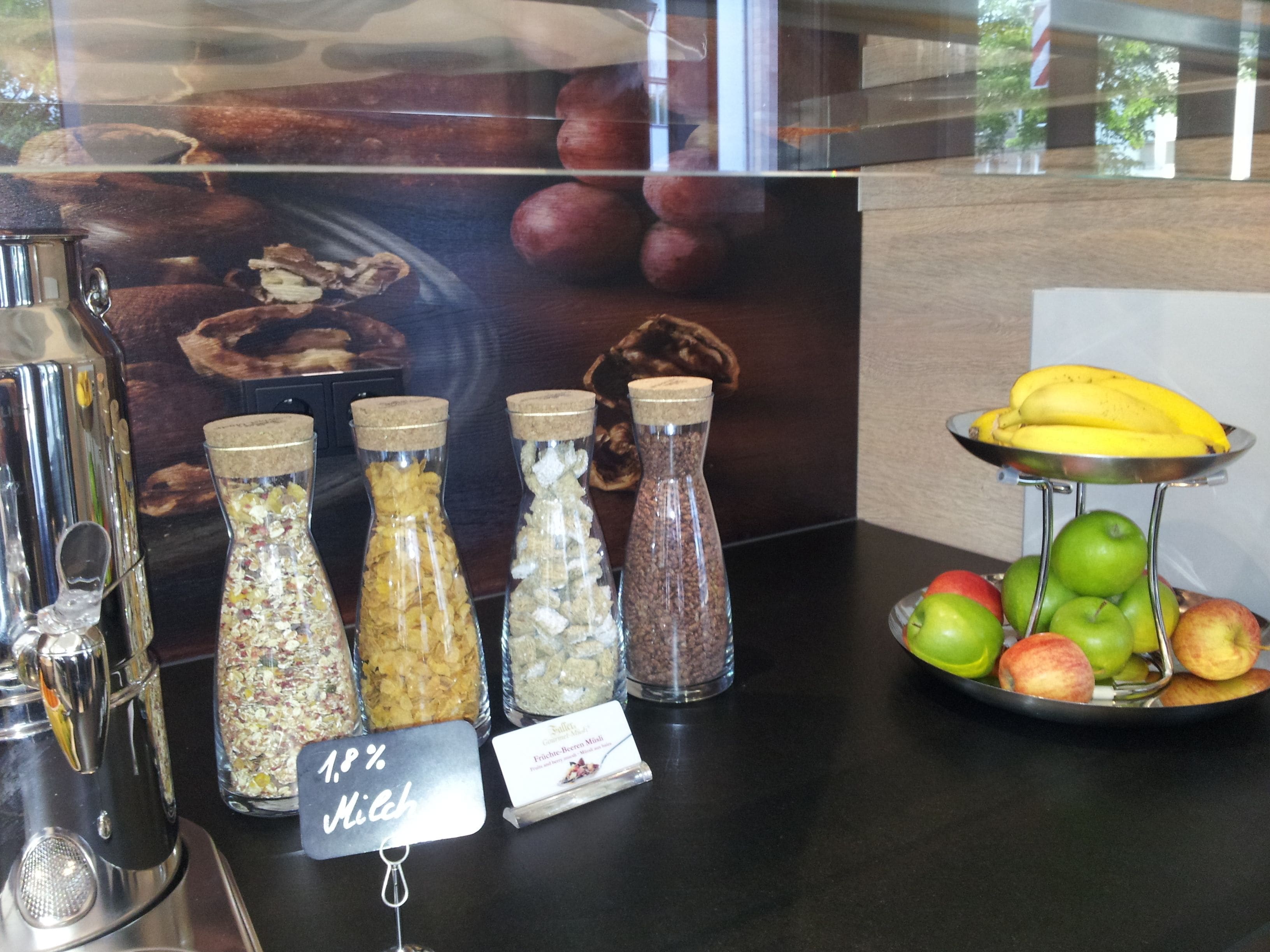 A display of food items including jars of granola and a tray of fruits.