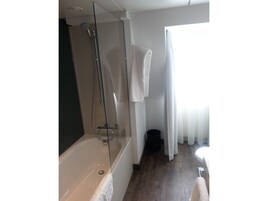 Un baño moderno con ducha de vidrio, bañera y retrete.