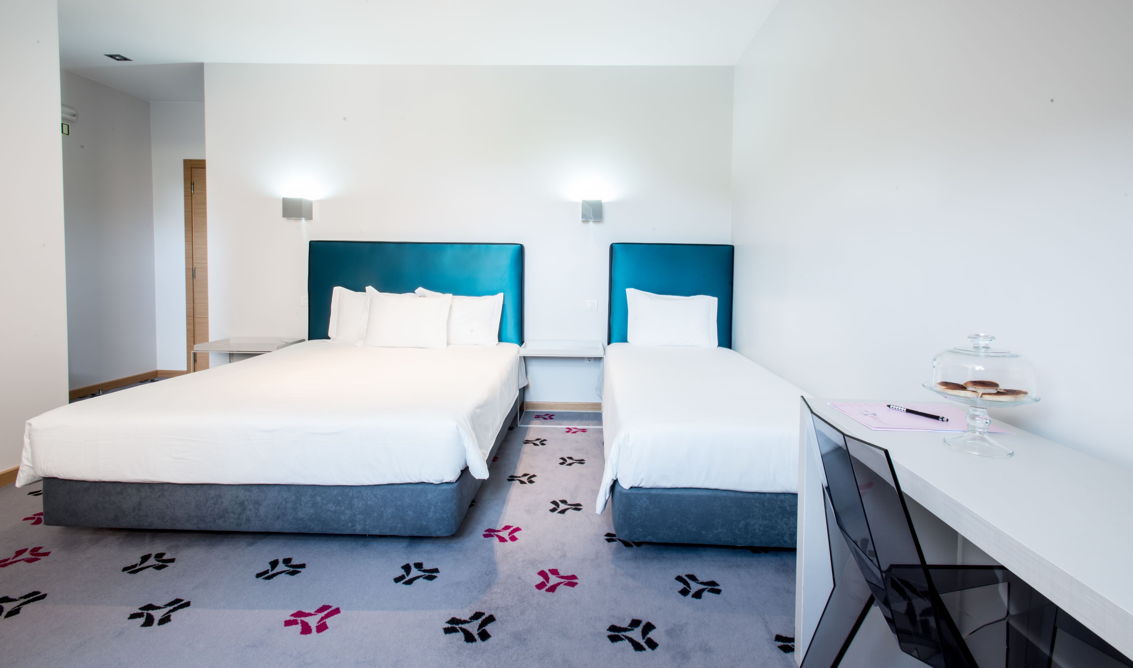 A hotel room with two beds, a desk, and a chair.