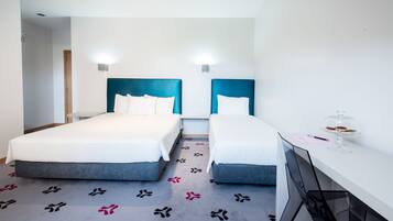 A hotel room with two beds, a desk, and a chair.