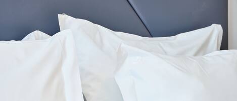 A bed with white pillows and a grey headboard.