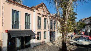 A hotel with a pink facade, large windows, and a black awning.