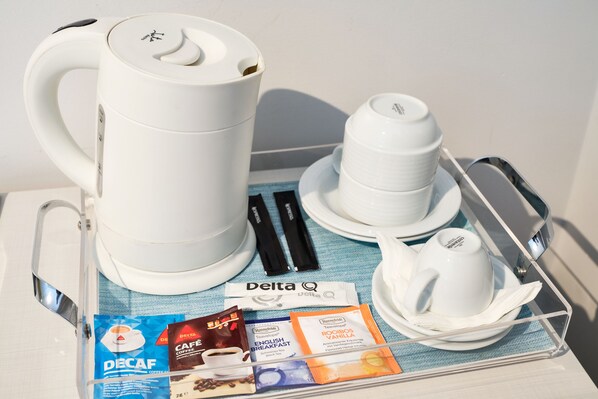 A coffee maker, a stack of cups, a tray with a spoon, and a Delta Q coffee pod. - Sintra Bliss Hotel (Sintra)