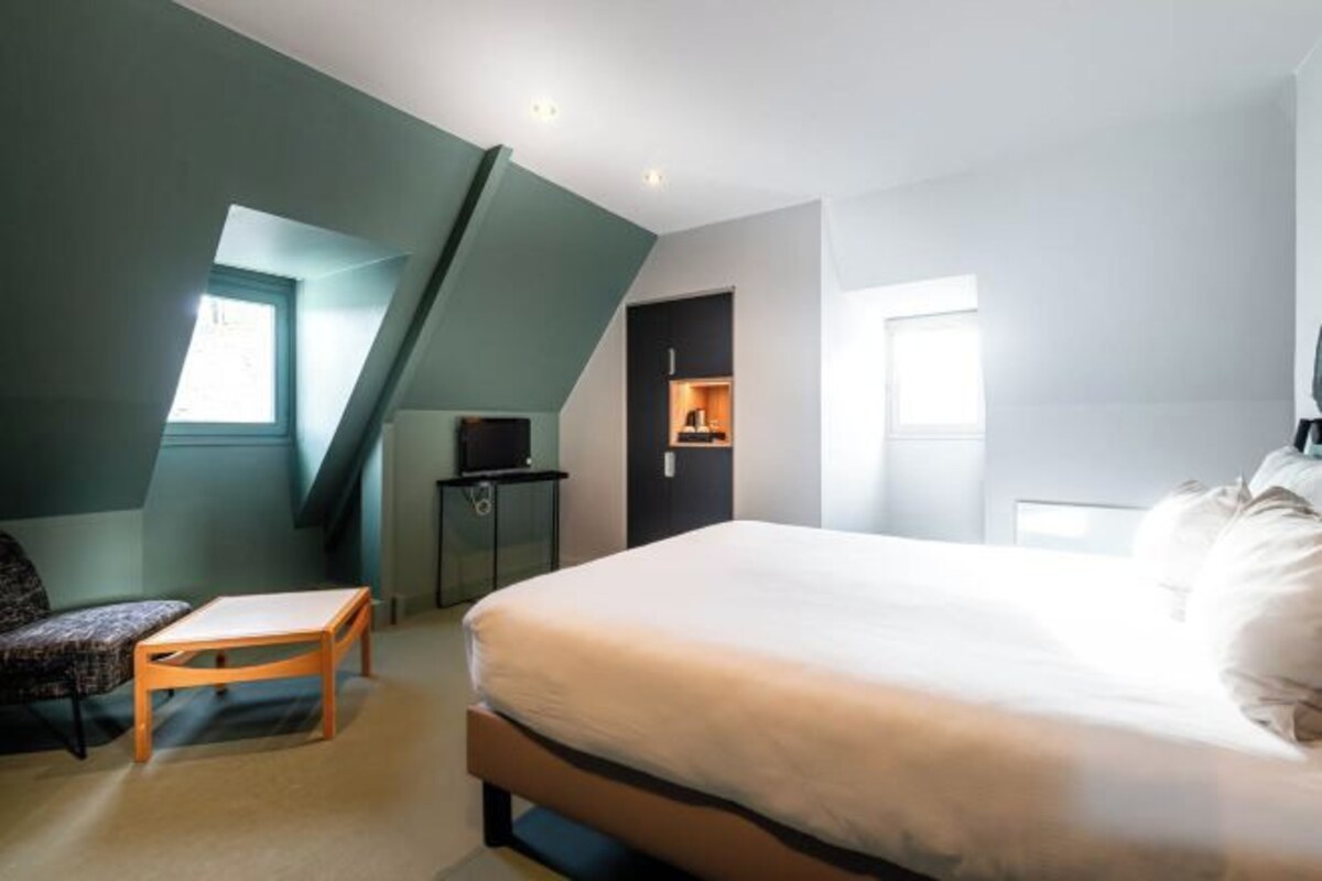 Een slaapkamer met een bed, een bureau en een stoel. Er is een raam en een deur.