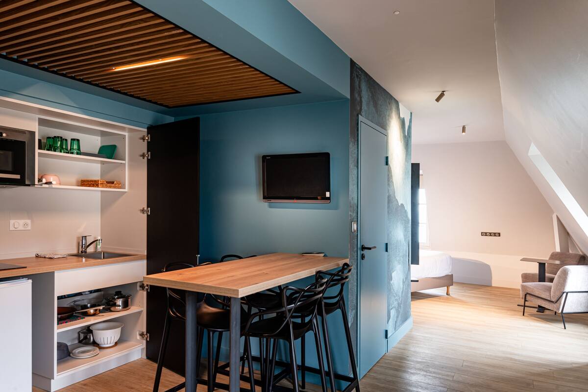 A modern kitchen with white cabinets, a wooden countertop, and a dining area with a wooden table and black chairs.