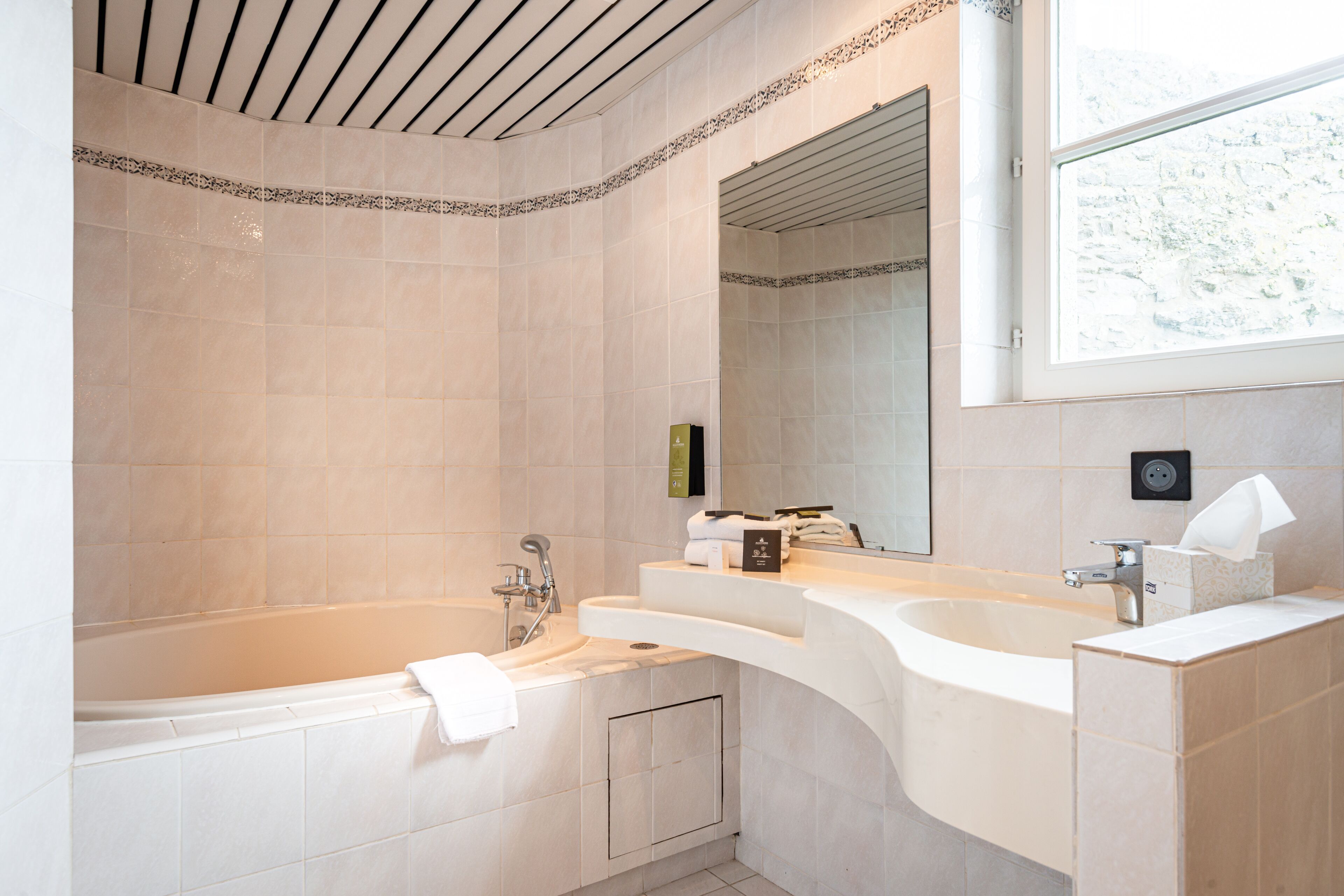 A modern bathroom with a bathtub, two sinks, and a large mirror.