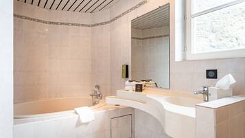 A modern bathroom with a bathtub, two sinks, and a large mirror.