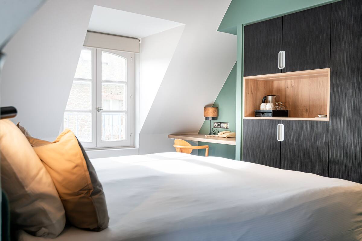 A bedroom with a bed, a desk, and a wardrobe.