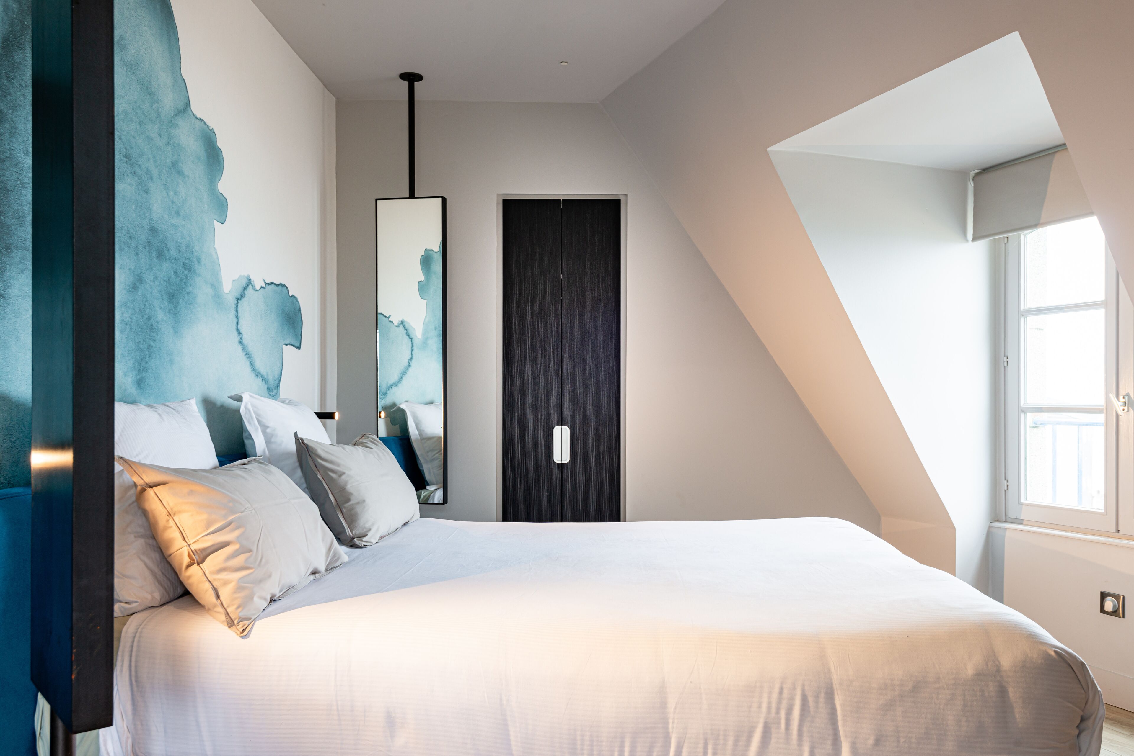 Ein modernes Schlafzimmer mit einem großen Bett, einem dunklen Kleiderschrank und einem Oberlicht.