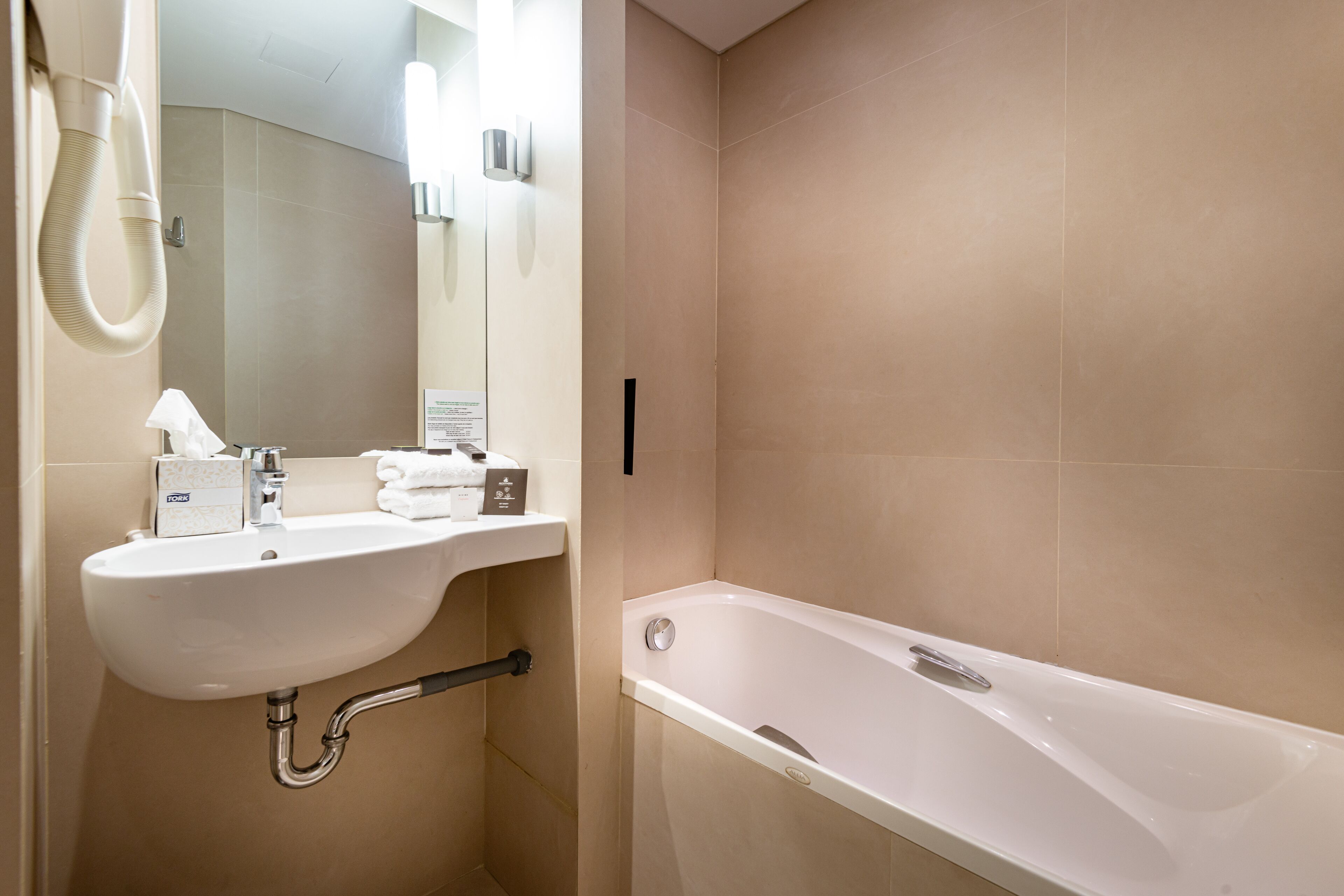 A modern bathroom with a sink, mirror, and bathtub.