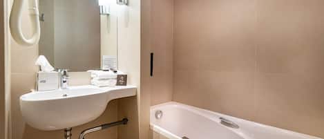 A modern bathroom with a sink, mirror, and bathtub.