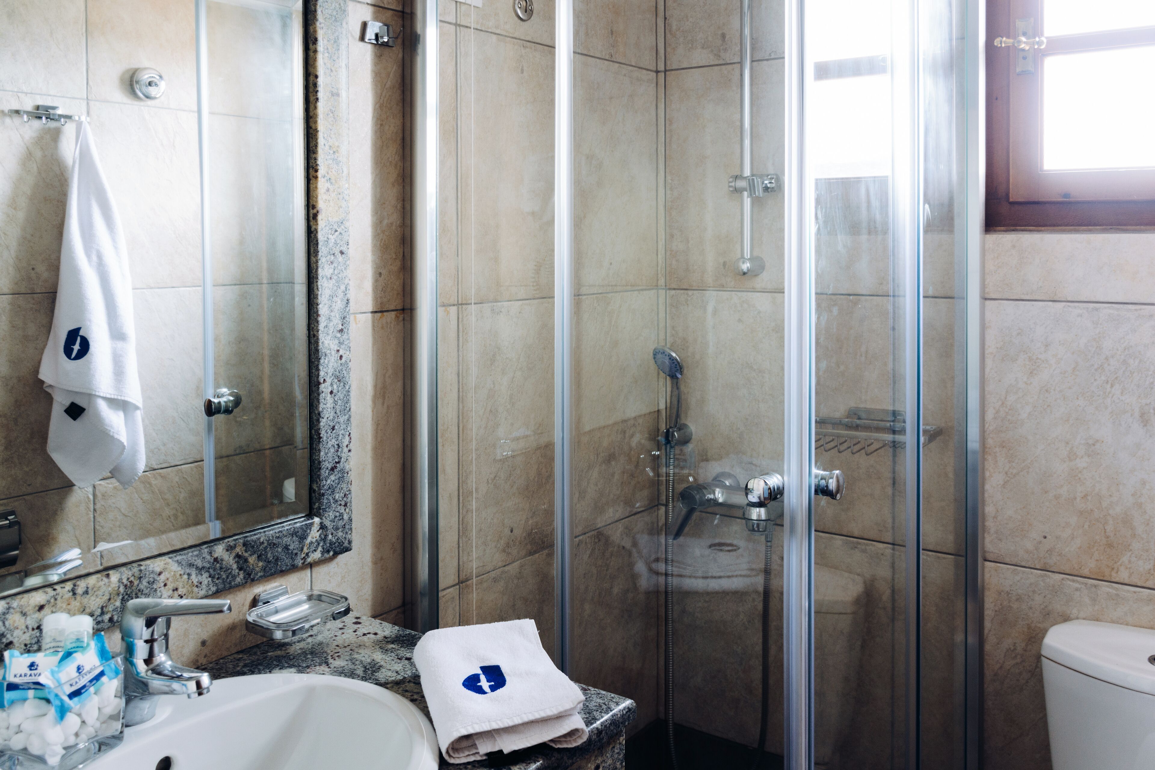 A bathroom with a glass-enclosed shower, a sink with a marble countertop, and a toilet.