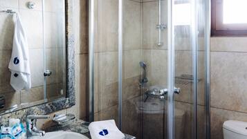 A bathroom with a glass-enclosed shower, a sink with a marble countertop, and a toilet.