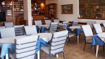 Un restaurante con varias mesas y sillas, una zona de bar y una pared de piedra con un cuadro.