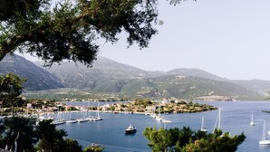 A marina with boats, a mountainous backdrop, and a coastal town. - Drymna Hotel (Dorida)