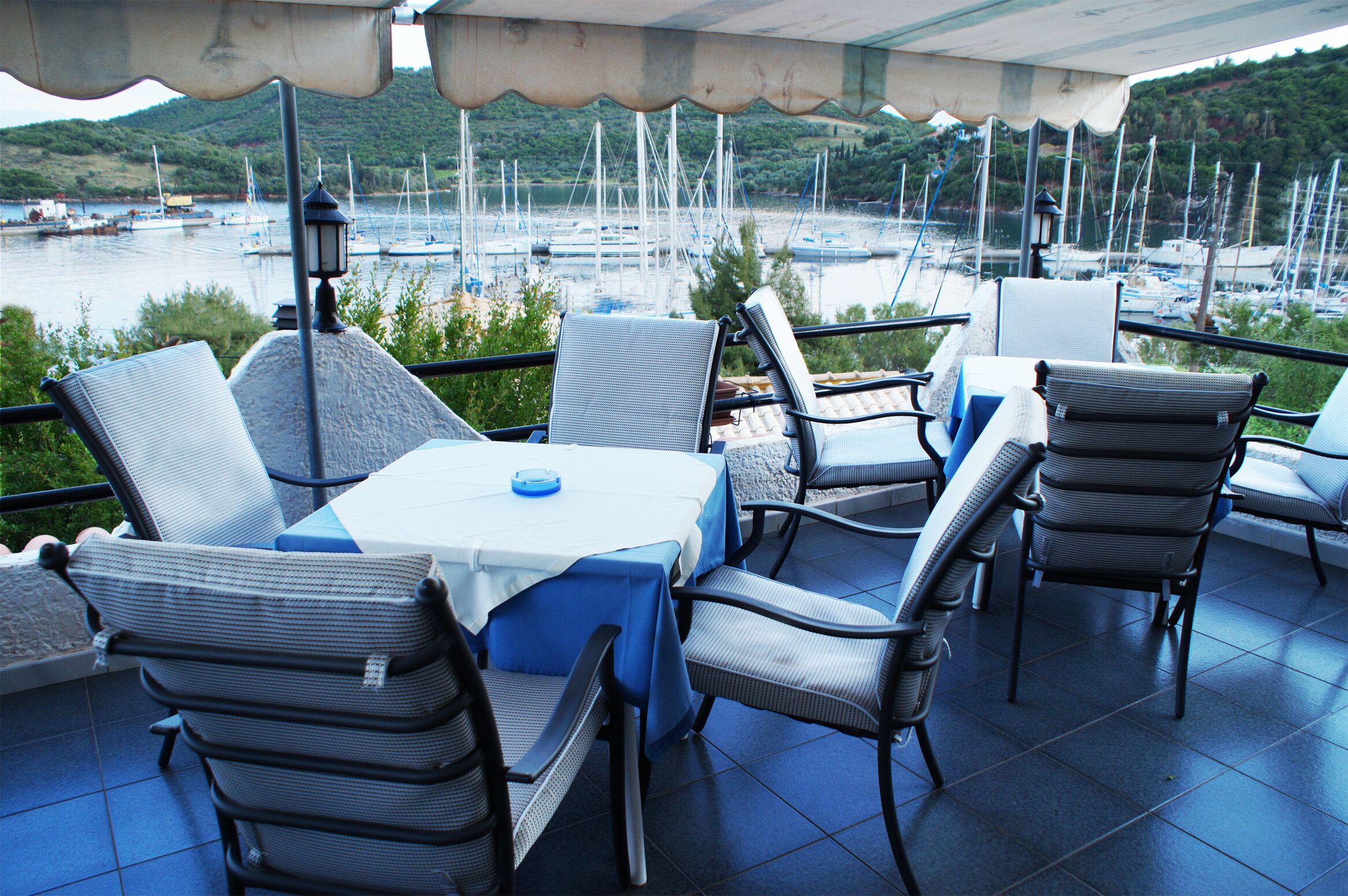 Una terraza con mesa y sillas, con vistas a un puerto deportivo y barcos.