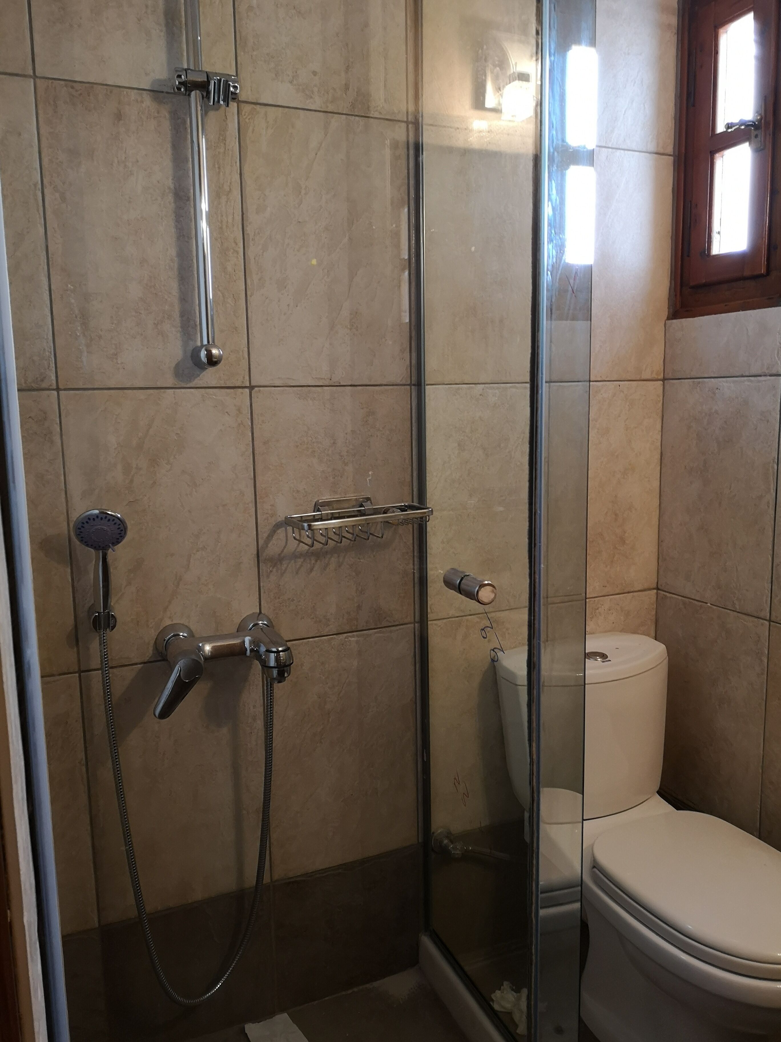 Une salle de bain avec une douche à parois de verre, des toilettes et un pommeau de douche.