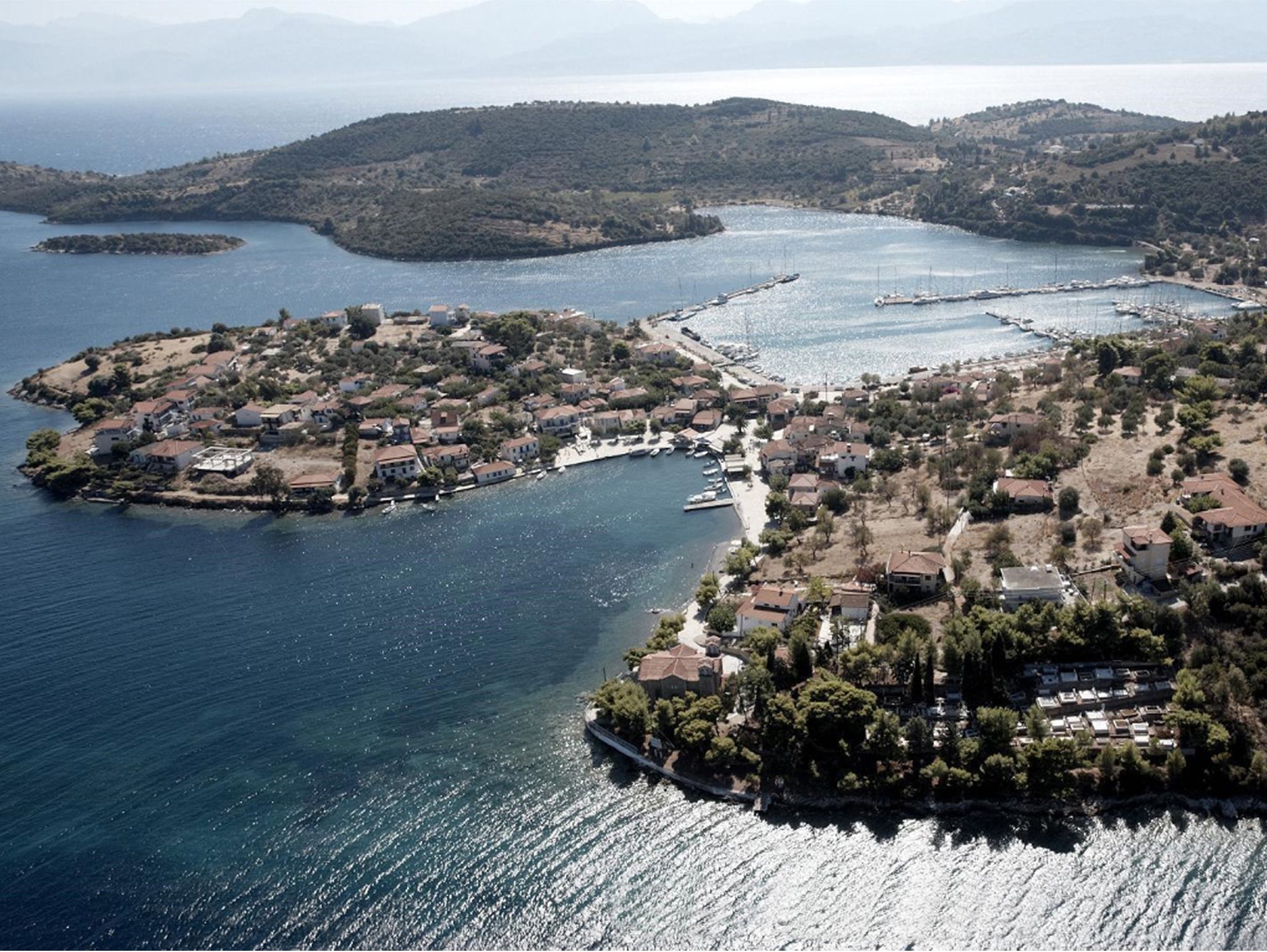 Vista aérea de un pueblo costero con casas, barcos y un puerto deportivo.