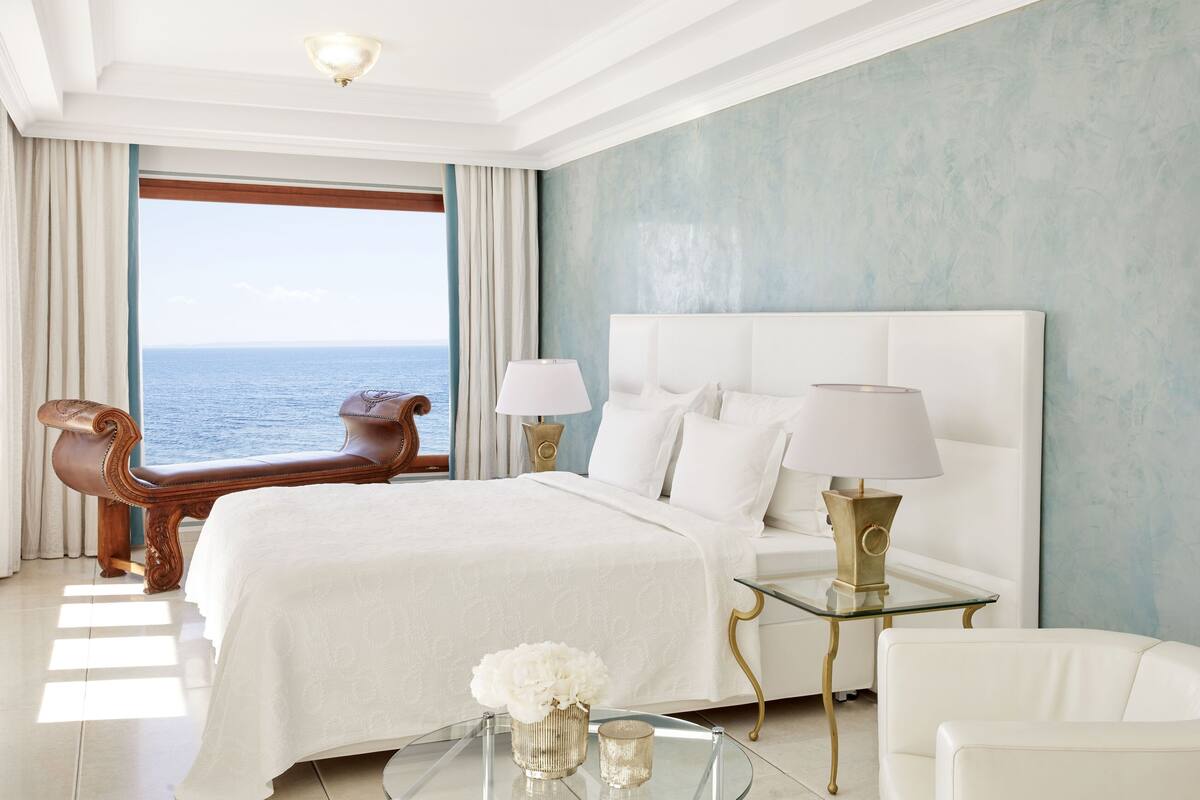 Een ruime slaapkamer met een groot bed, uitzicht op zee en een moderne inrichting.