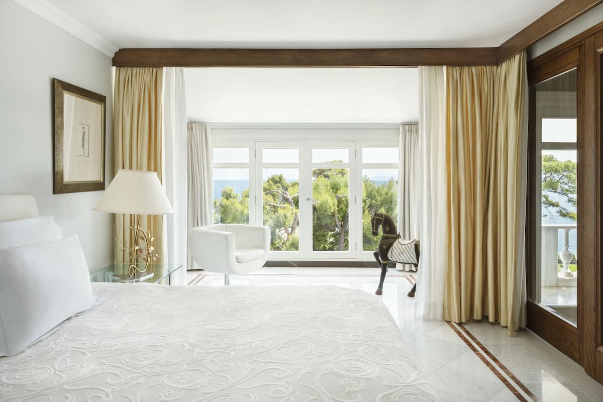 Een hotelkamer met een groot bed, een stoel, een lamp en uitzicht op de omgeving.