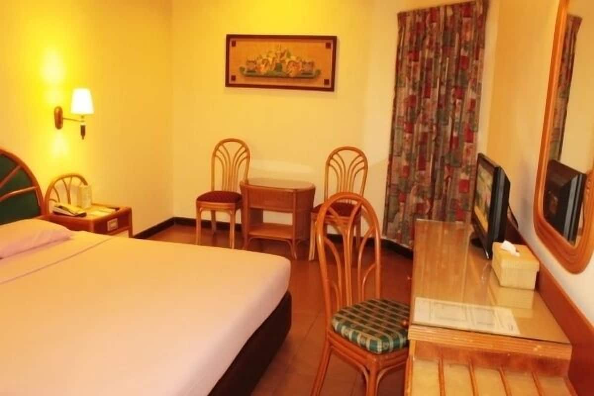 A hotel room with a bed, a desk with a chair, a television, and a painting on the wall.