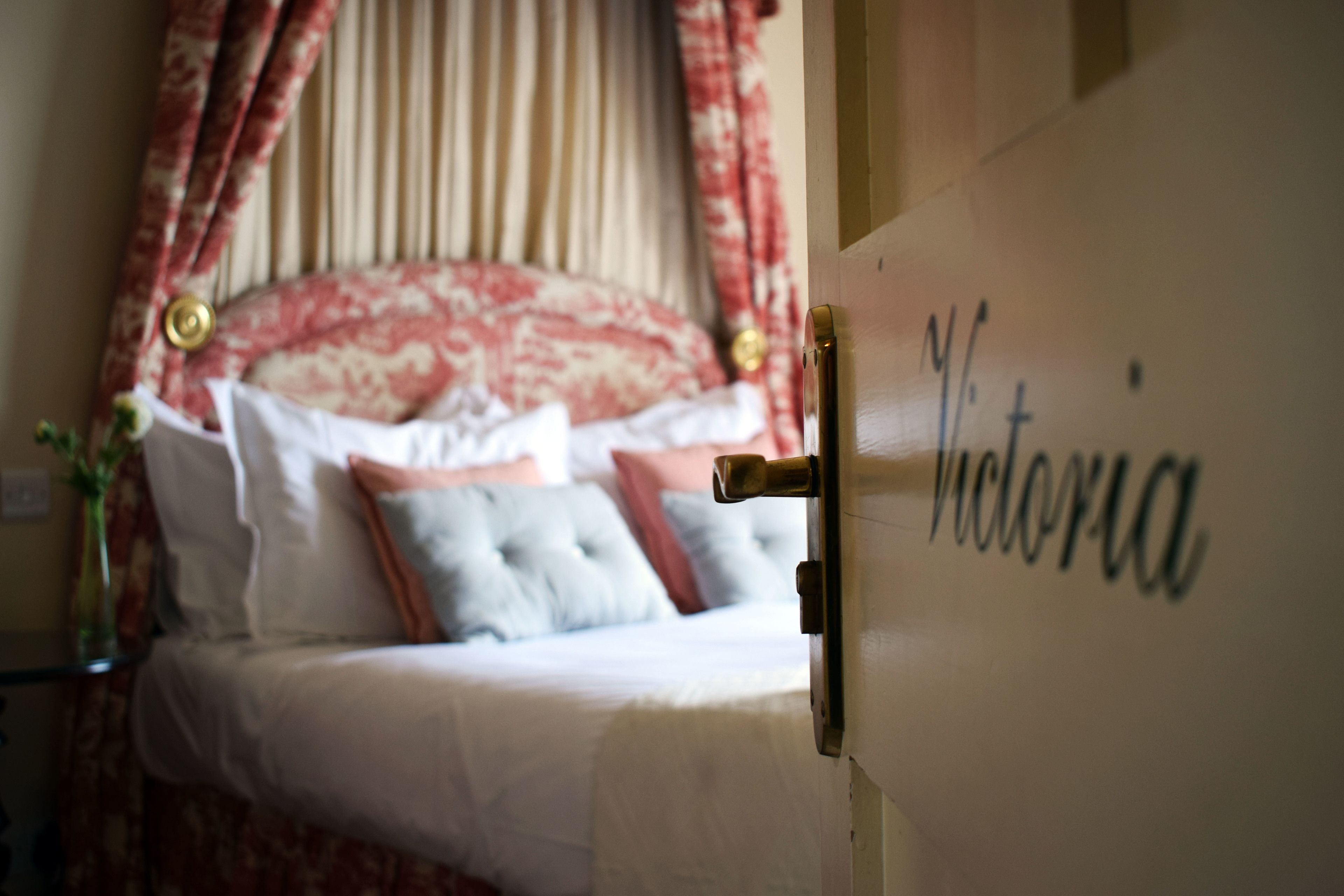 Un lit à baldaquin et une porte sur laquelle est inscrit le nom « Victoria ».