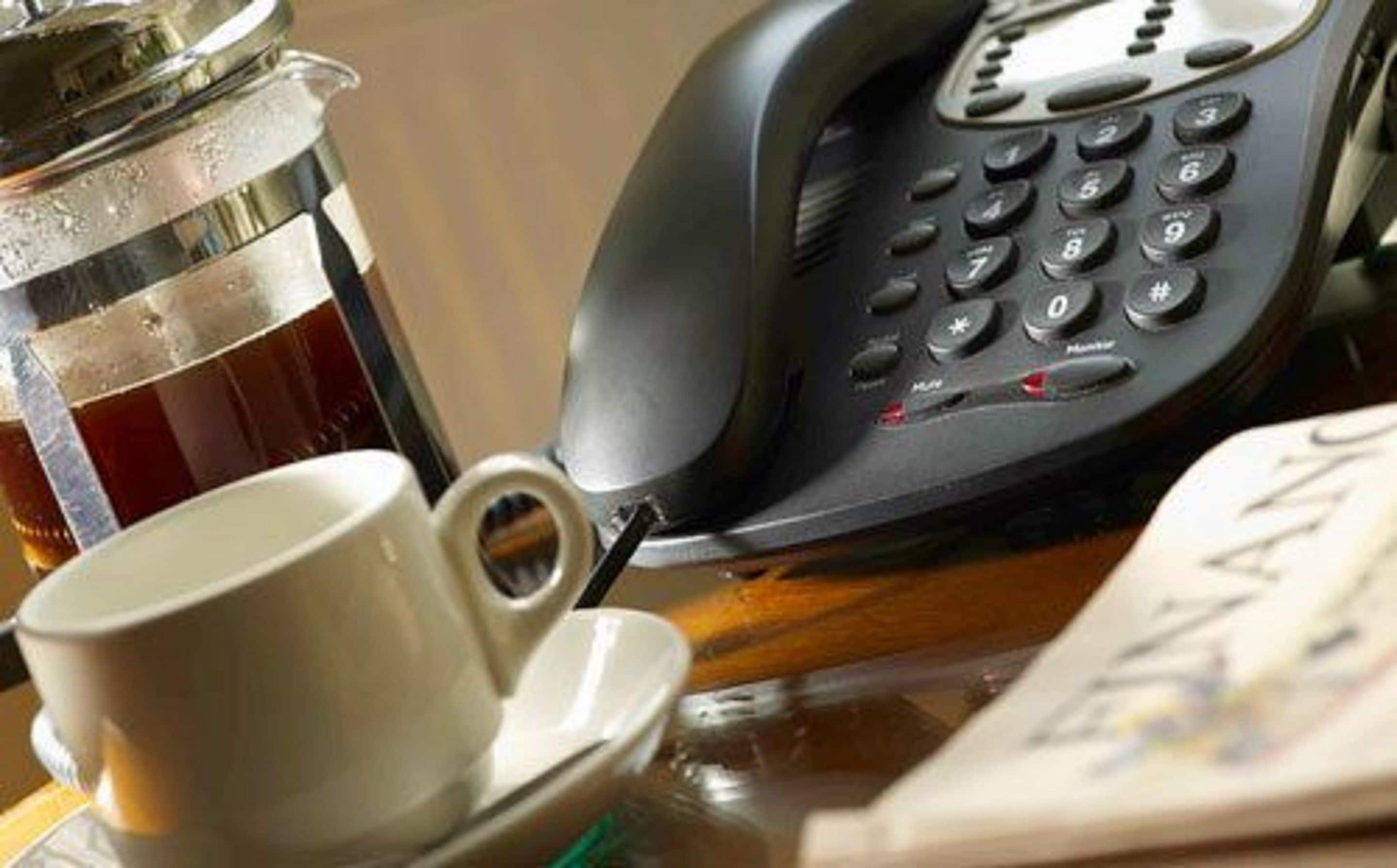 A coffee cup, a telephone, and a book on a table.