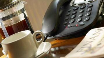 A coffee cup, a telephone, and a book on a table.