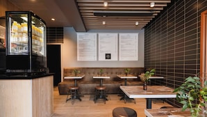 Interior moderno de café, com balcão, área de estar, painéis de menu e geladeira.