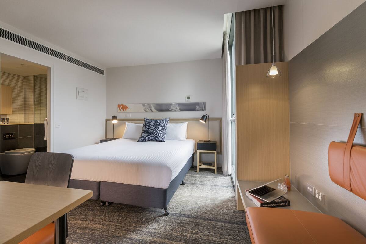 Una habitación de hotel moderna con una cama grande, un escritorio, una silla y un sofá.