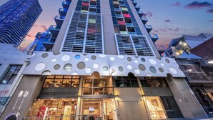 A modern high-rise hotel with a unique facade featuring circular cutouts and balconies with colorful accents.