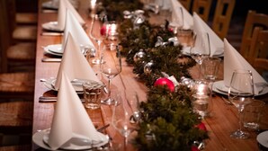 A long dining table set with white napkins, glasses, and candles, decorated with greenery and red ornaments. - XII Apostel Hotel Albergo (Cologne)