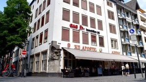 A building with a white facade, multiple windows with brown shutters, and a sign for 'XII APOSTEL'. - XII Apostel Hotel Albergo (Cologne)