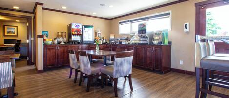 A hotel dining area with wooden flooring, a central round table, and multiple chairs.