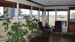 A room with large windows, a potted plant, two chairs, a table, and a lamp. - Uptown Inn (Port Angeles)
