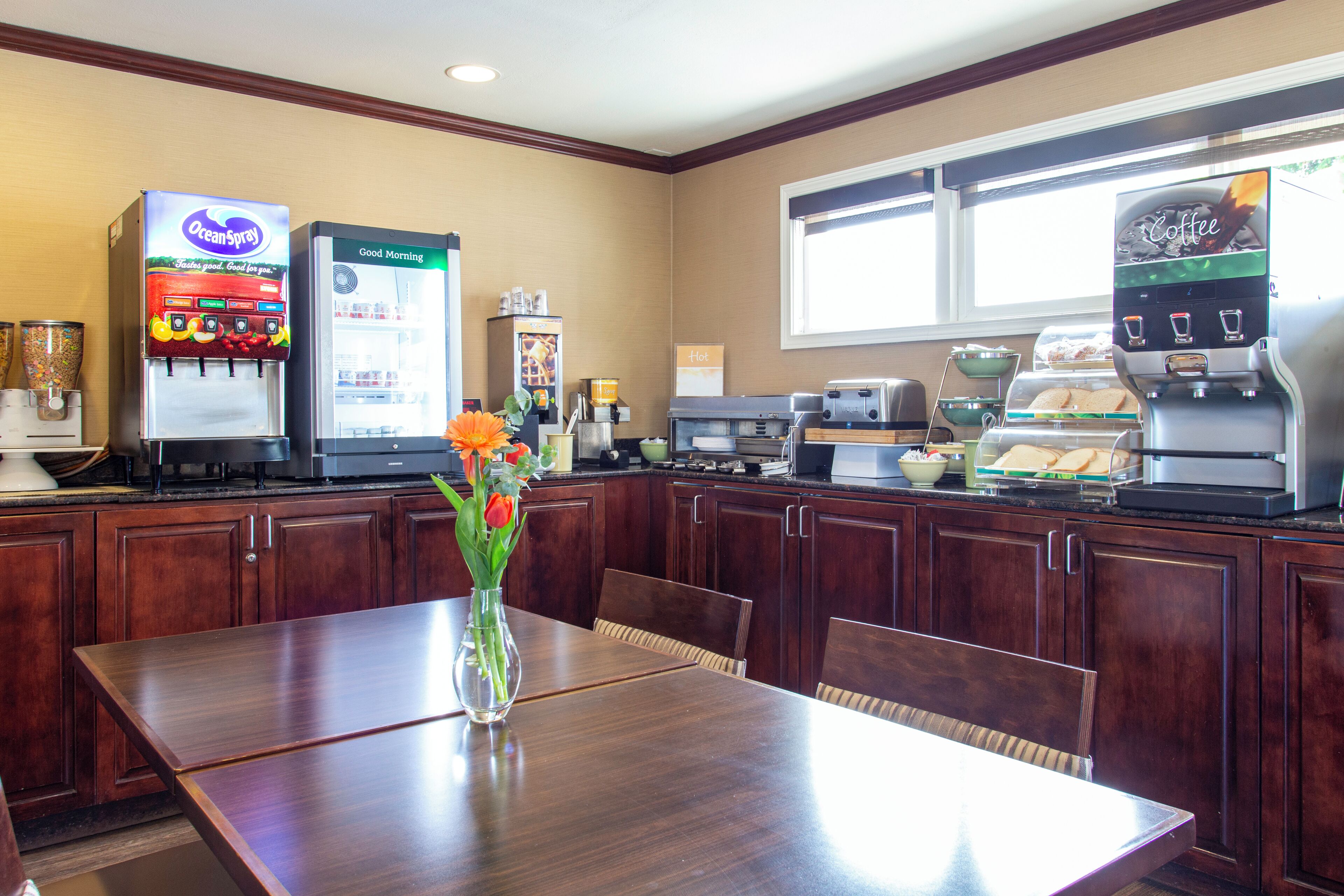 A restaurant with a coffee machine, a beverage dispenser, and a food display.